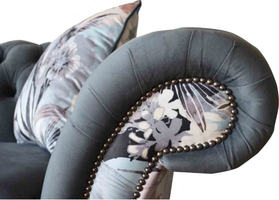 Een opvallende driezitsbank in Chesterfield-design met subtiele grijze bloemendecoratie.