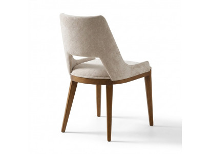 Een laconieke, moderne stoel met hoge poten van hout en bekleding in een prettige, lichte crèmekleur voor de eetkamer.